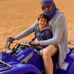 man with his Baby Boy riding Quad Bike in Desert