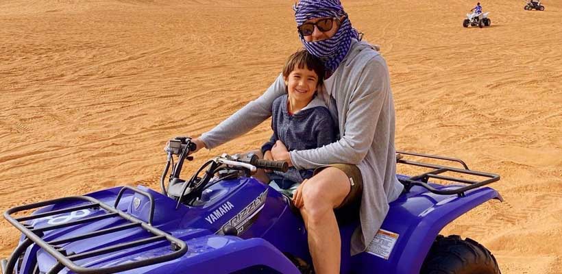 man with his Baby Boy riding Quad Bike in Desert