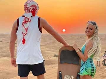 Man and Woman Holding Sand Board at Sunrise Desert Safari Tour