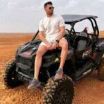 Tourist Man Sitting on Dune Buggy in Arabian Desert