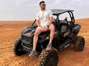 Tourist Man Sitting on Dune Buggy in Arabian Desert