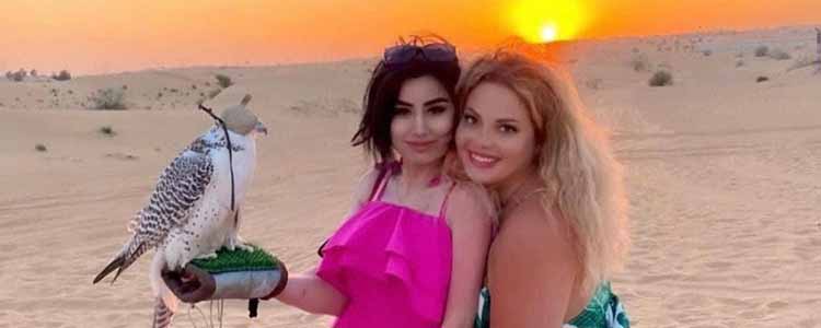 Two Tourist Girls Holding falcon in Dubai Desert