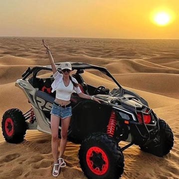 Tourist Girl standing with CAN AM Maverick Dune Buggy Ride Dubai Desert at Sunset