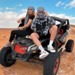 Tourist Couple Sitting on top of Dune Buggy in the Dubai Desert