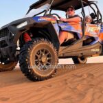 Tourist Man Riding 4-Seater Dune Buggy with his Baby in the back during Desert Safari